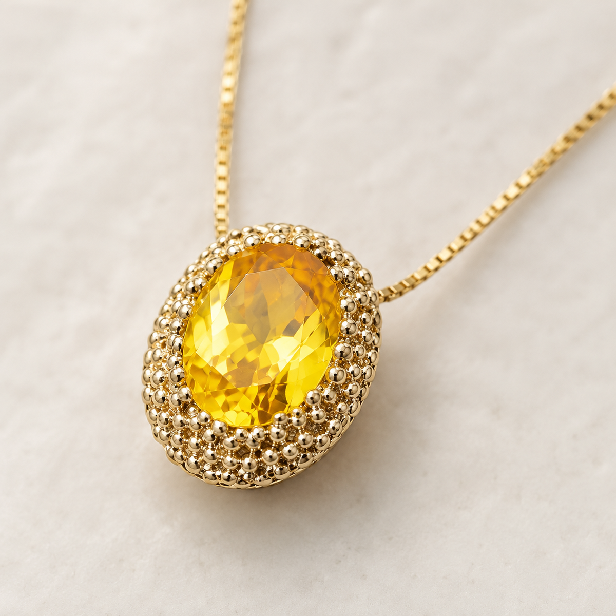 Close view of the faceted oval citrine pendant in a gold-tone setting.