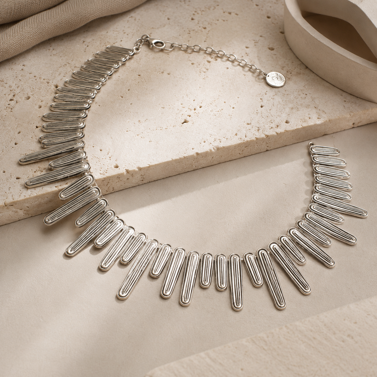 Angled view of a silver-tone wave bar collar necklace.