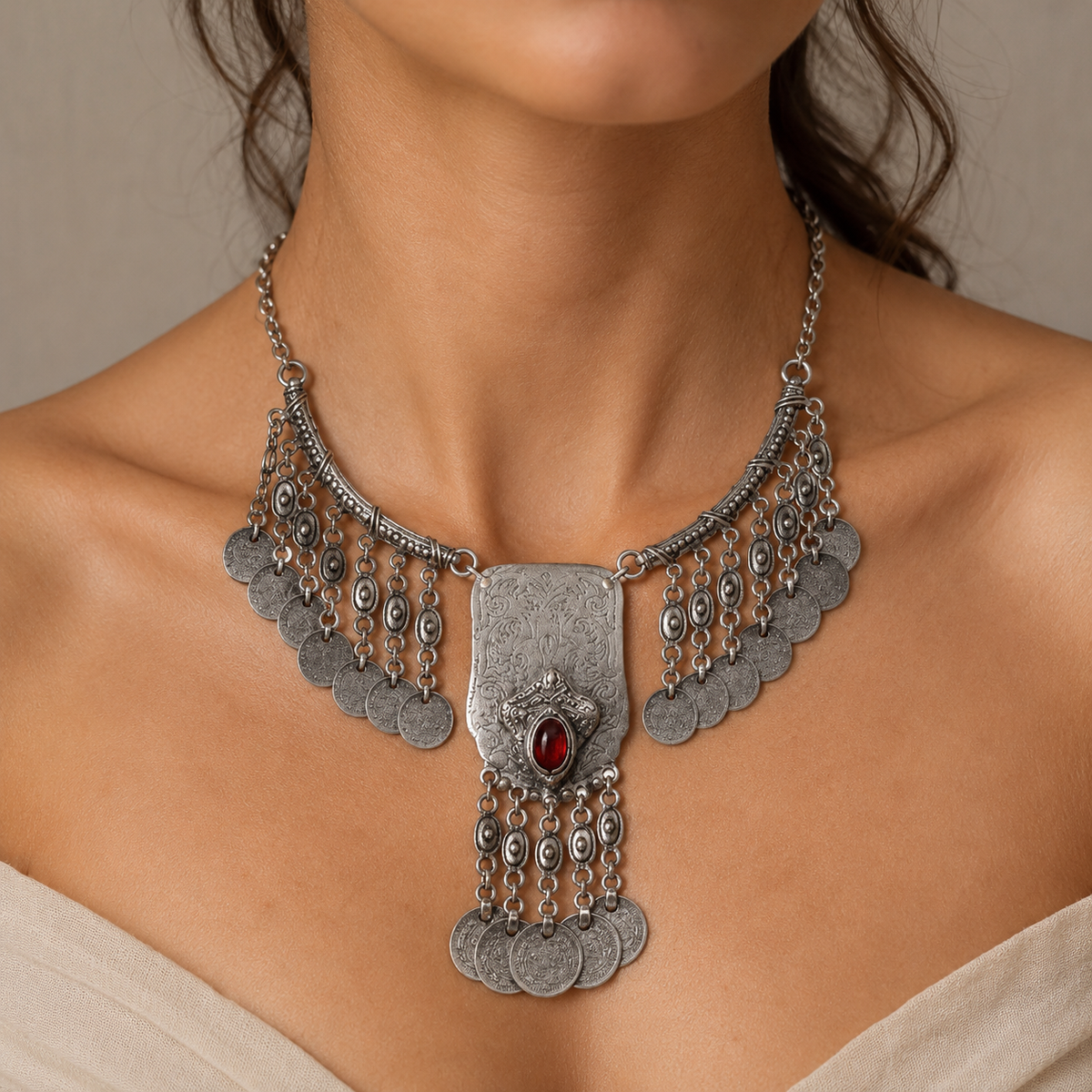 Silver-tone statement necklace with textured coin fringe and a red stone center.