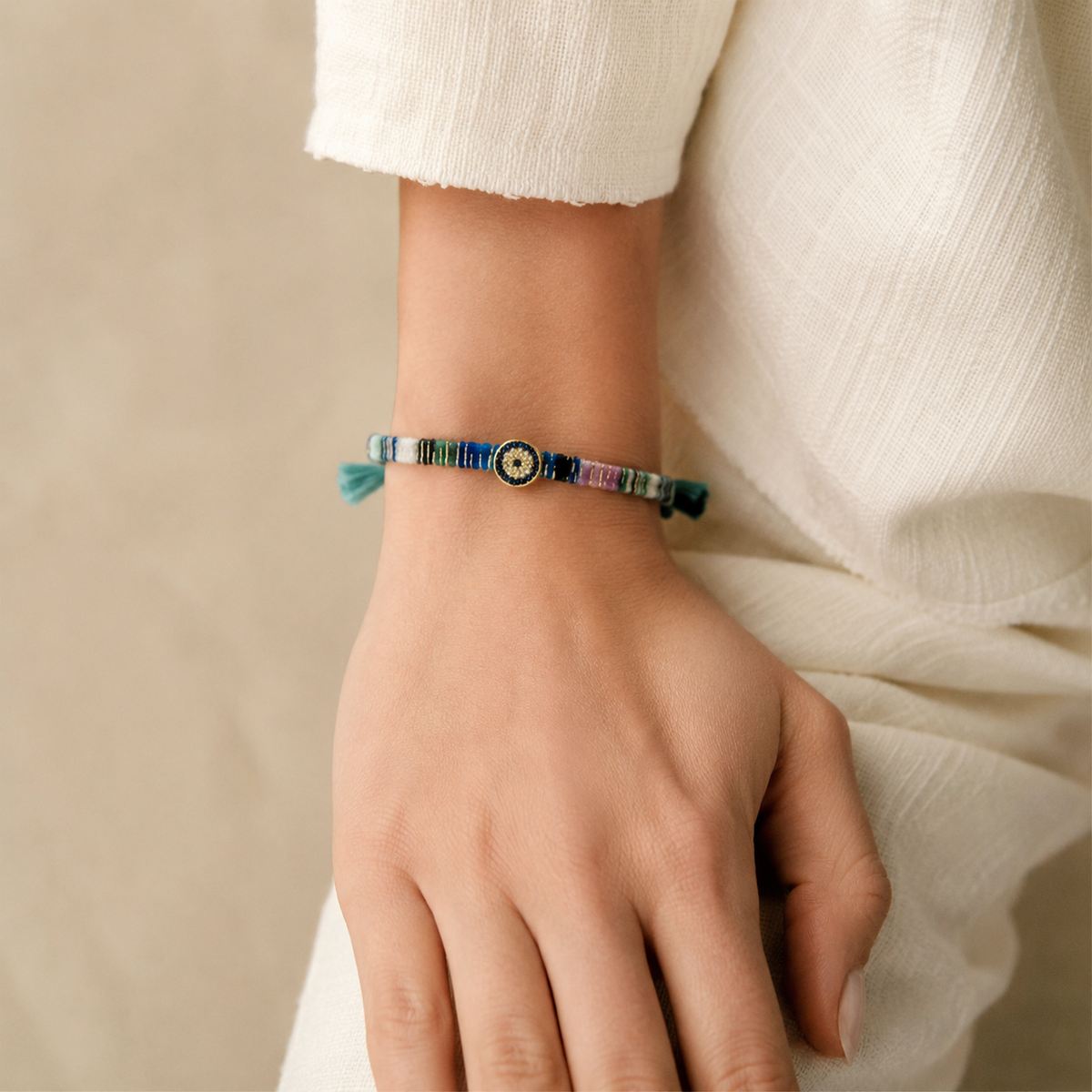 Colorful fabric bracelet with a jeweled evil eye centerpiece and braided ties.
