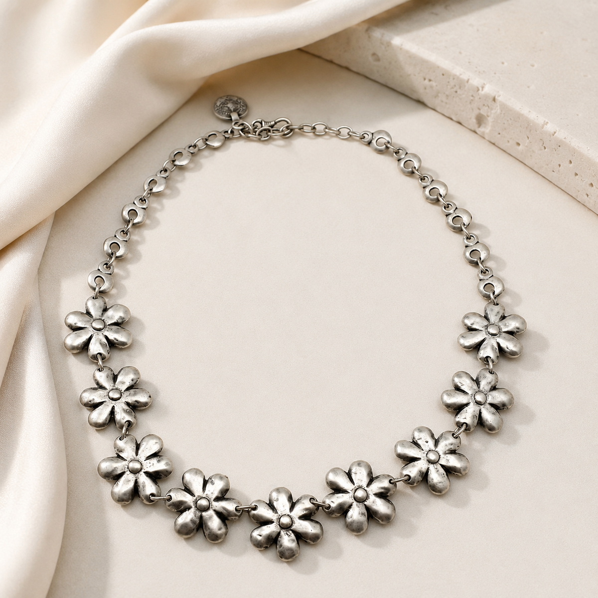 Silver-tone floral necklace with linked flower charms in a soft curved shape.