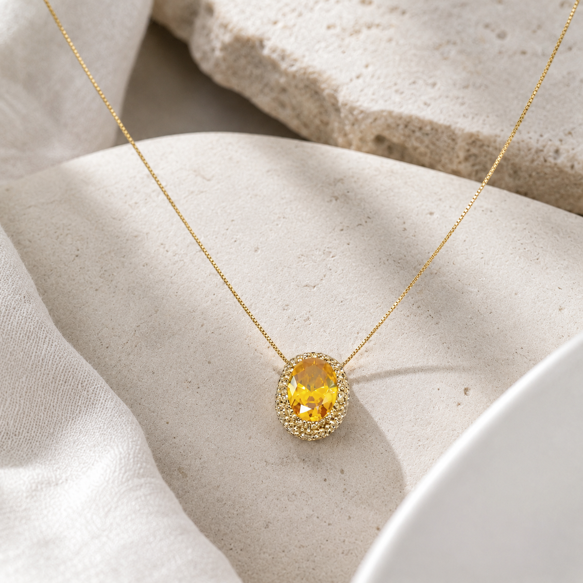 Angle view of a gold-tone necklace with an oval citrine pendant.
