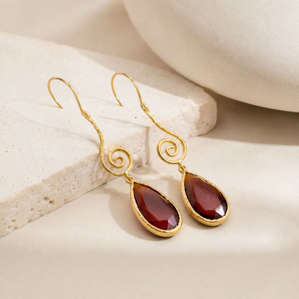 Angle view of gold-plated spiral drop earrings with brown teardrop accents.