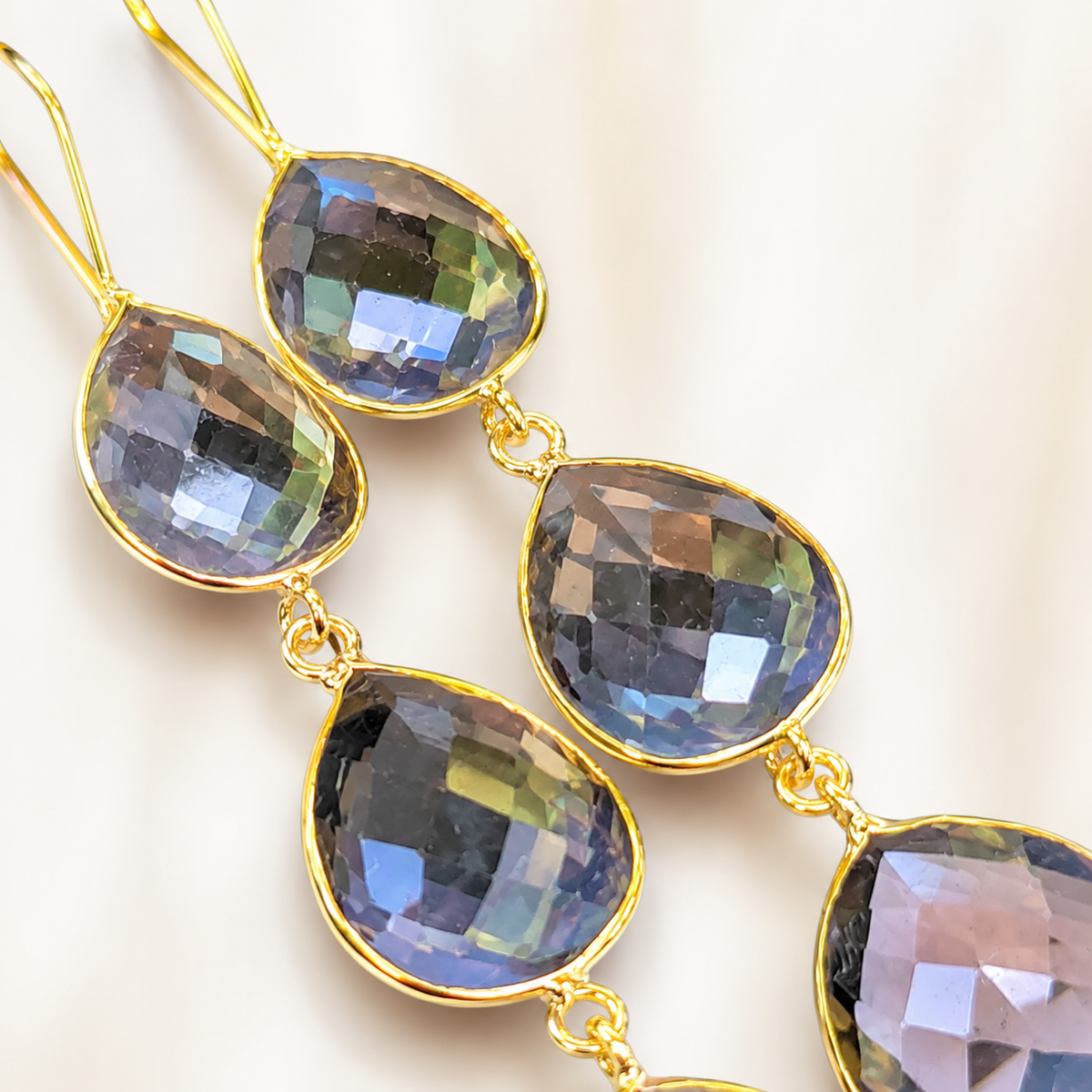 Close-up of faceted smoky quartz teardrop earrings with gold-plated settings.
