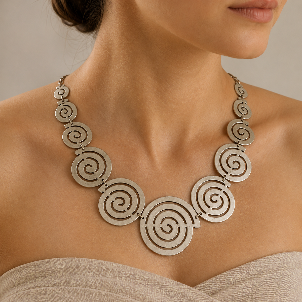 Spiral circle statement necklace shown from the front in a gold-tone finish.