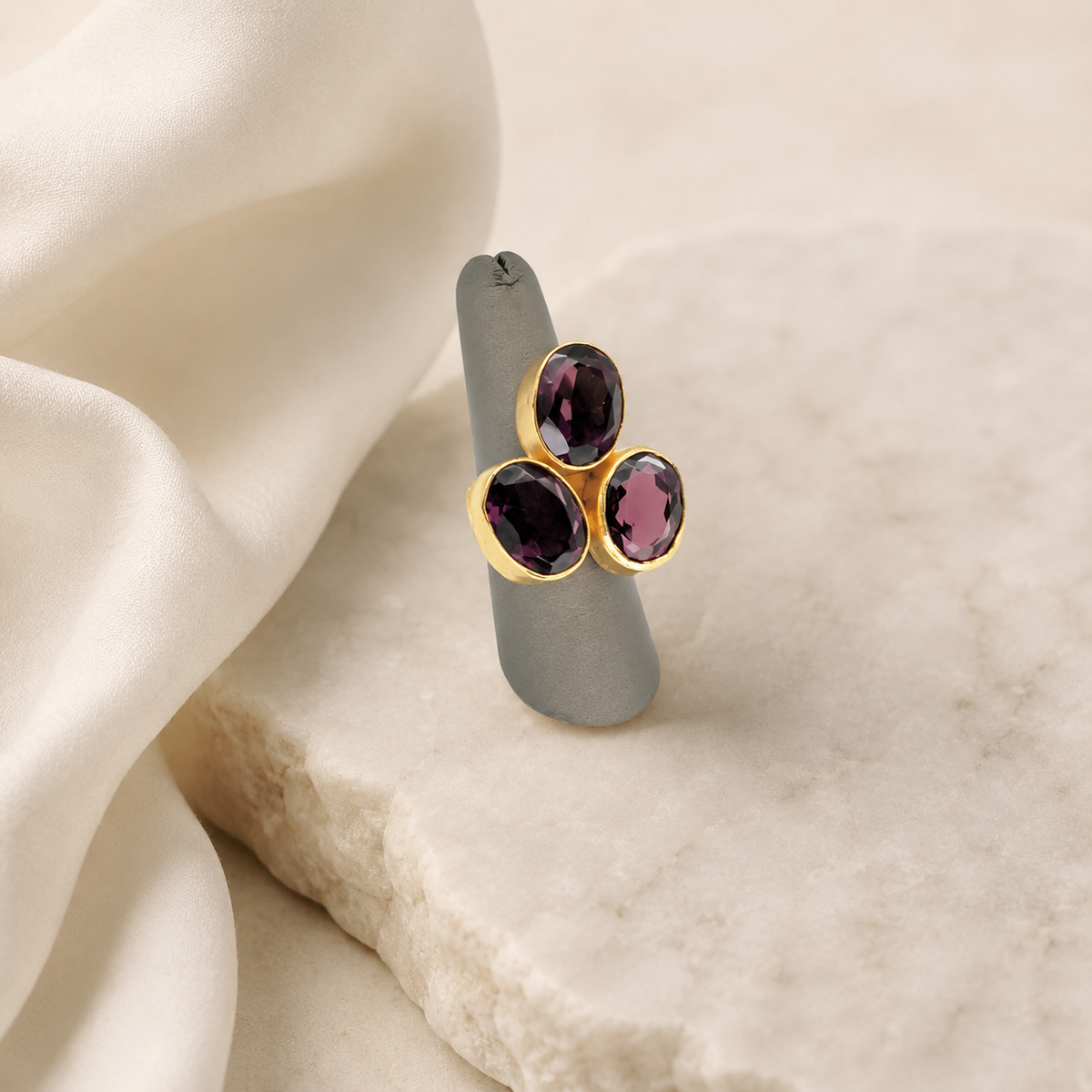 Three stone amethyst ring with a polished gold-plated setting.