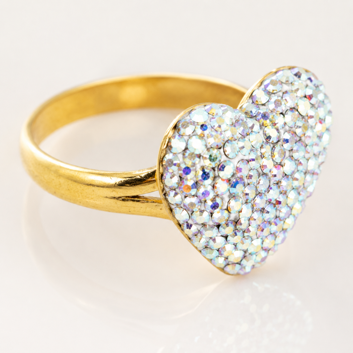 Close-up of a heart-shaped crystal ring with a polished gold-tone band.