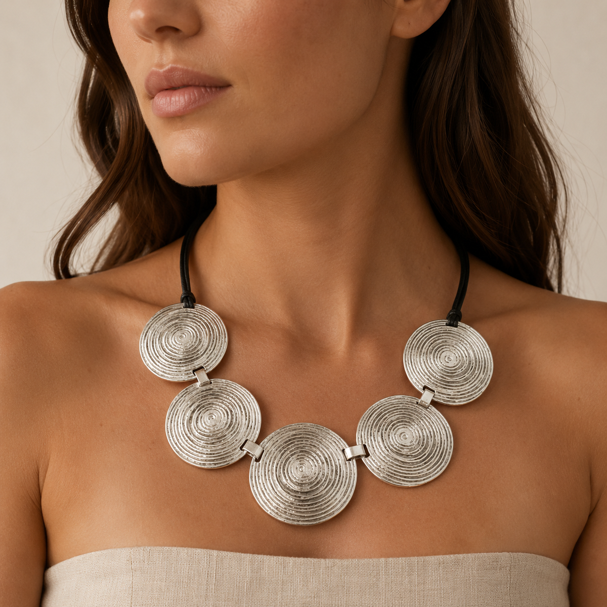 Silver spiral disc necklace shown on a model.