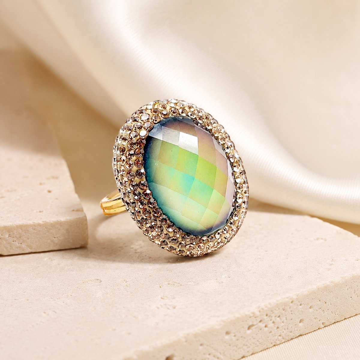 Gold-plated statement ring with a large faceted center and sparkling halo on a white background.