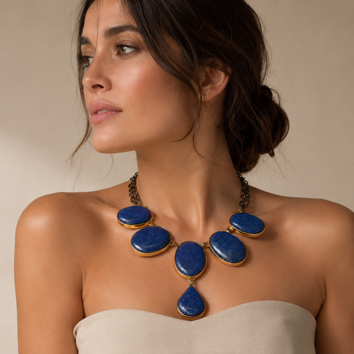 A statement necklace with blue oval stones, gold-tone frames, and a teardrop pendant.