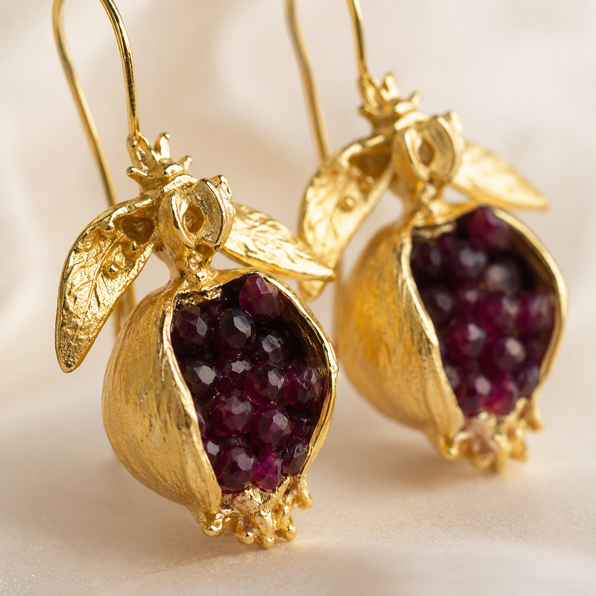 Close view of textured gold-plated earrings with red stones.