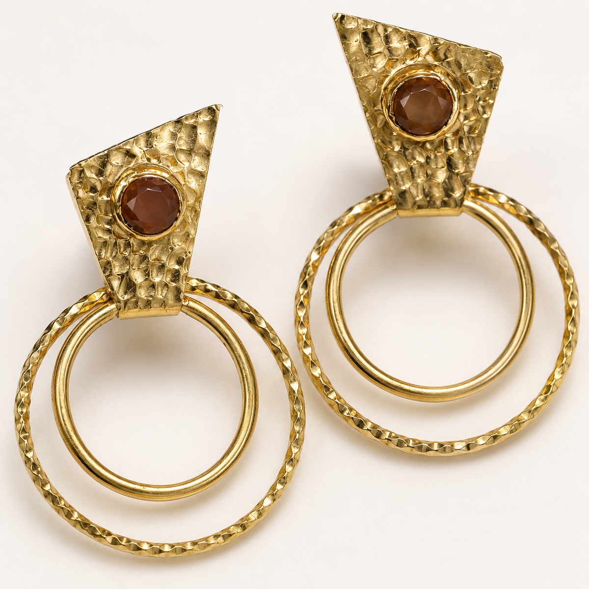 Close view of textured gold-plated earrings with a brown center accent.