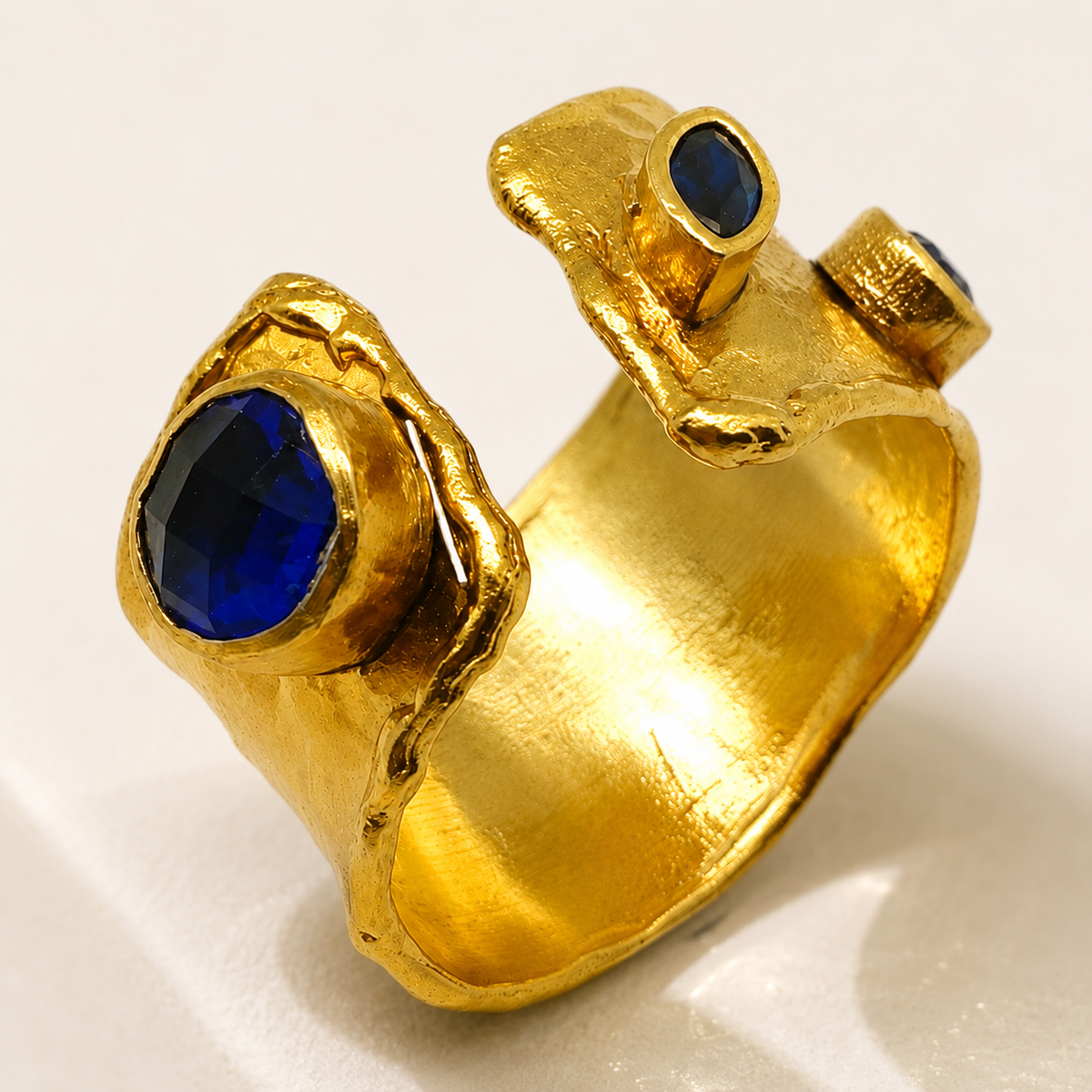 Close view of the textured gold-plated ring and blue stones.