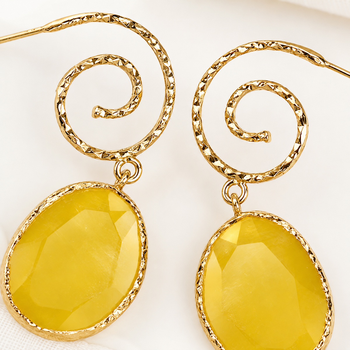 Close view of yellow faceted oval drops and spiral gold-plated tops.