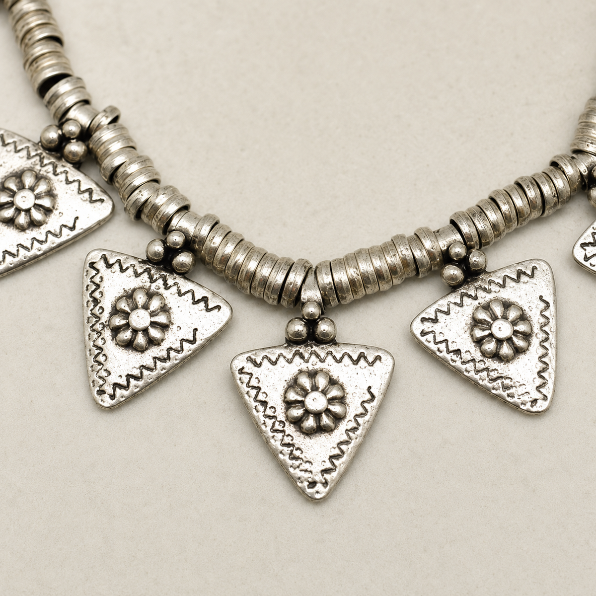 Close view of the textured silver-tone triangle charm and floral detail.
