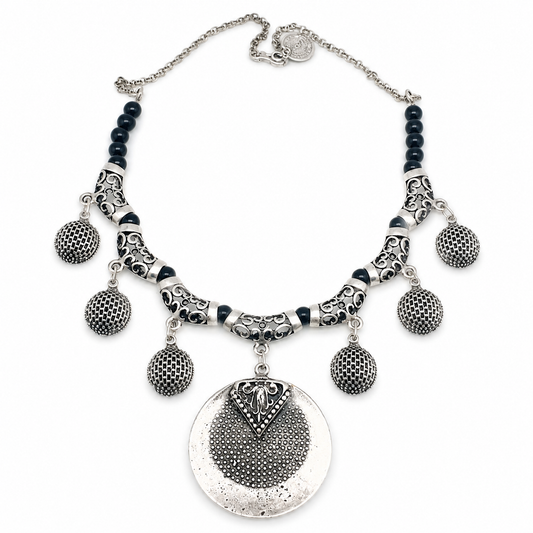 Black bead necklace with a silver-toned medallion pendant and textured charms.