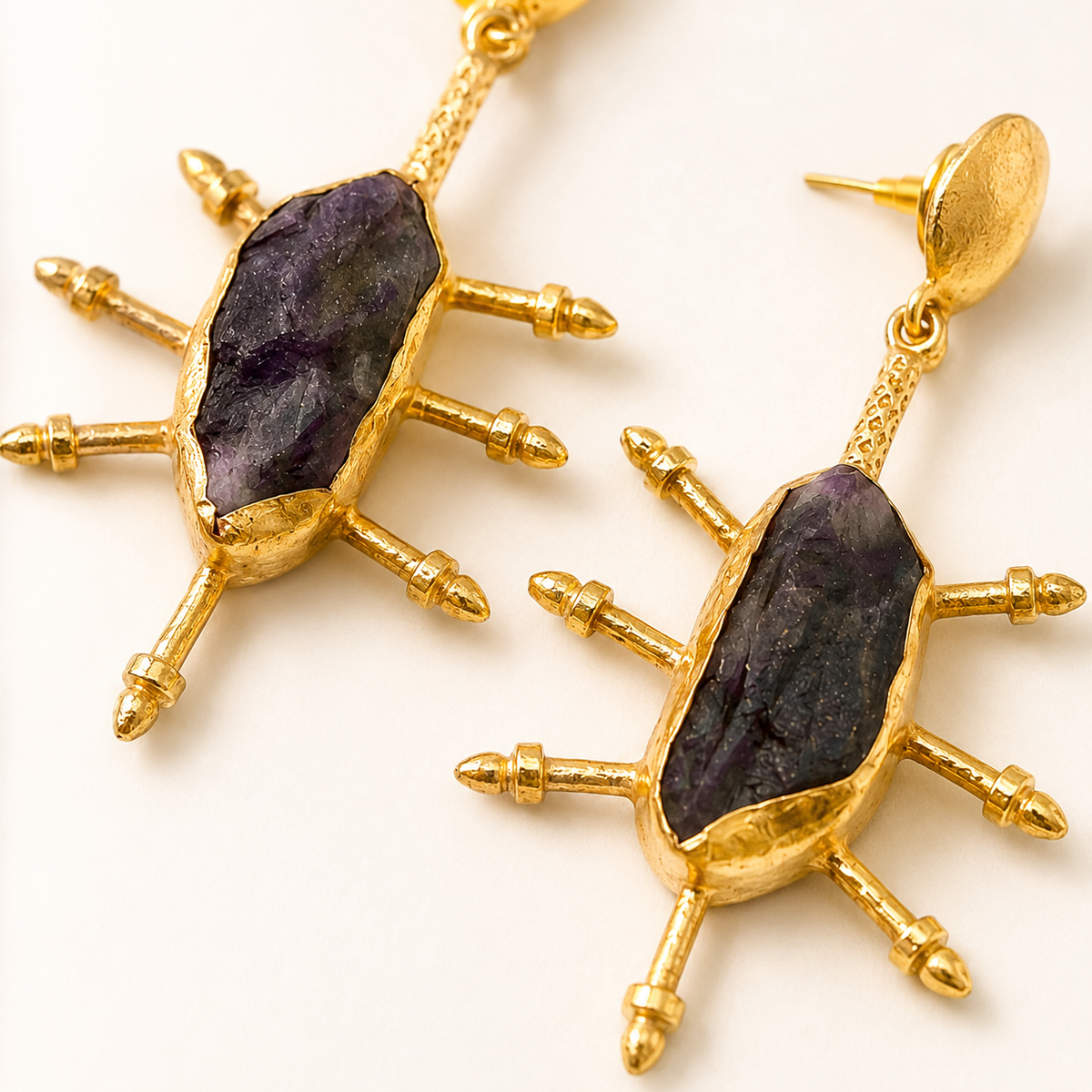 Close view of raw amethyst and gold-plated spike earrings.