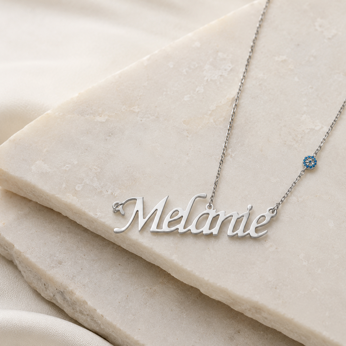 Angle view of a silver-tone name necklace with a polished script pendant.