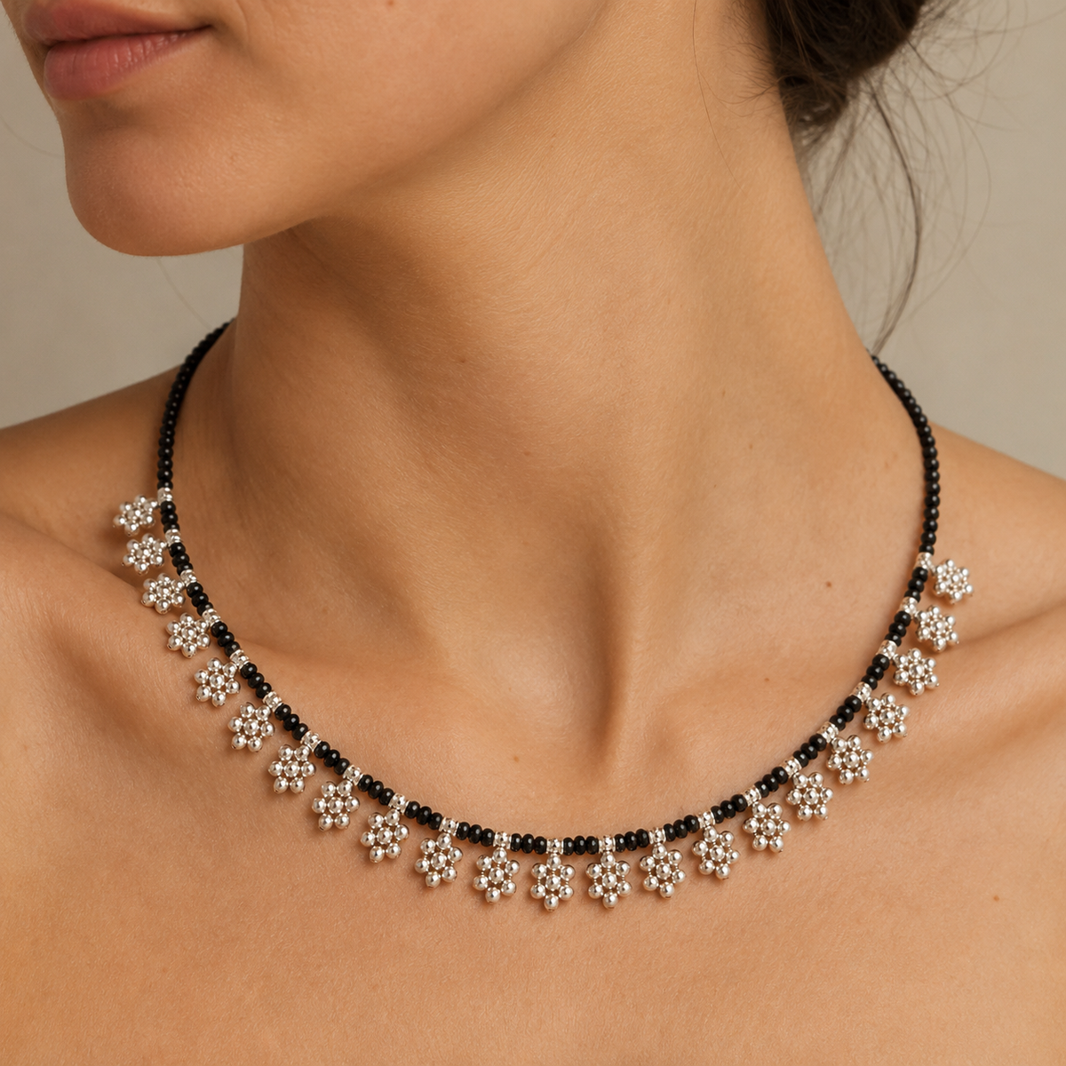 Black bead necklace with floral fringe accents shown on a white background.