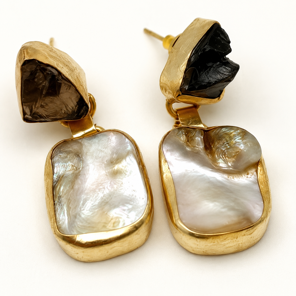 Close-up of gold-plated earrings with smoky quartz and mother of pearl details.