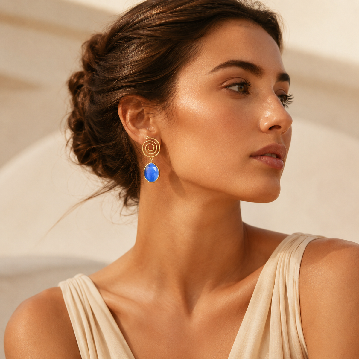 Front view of spiral gold-tone earrings with blue faceted drops.