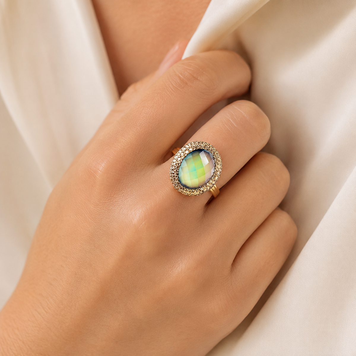 Gold-plated statement ring shown at an angle with a faceted mood stone-style center.
