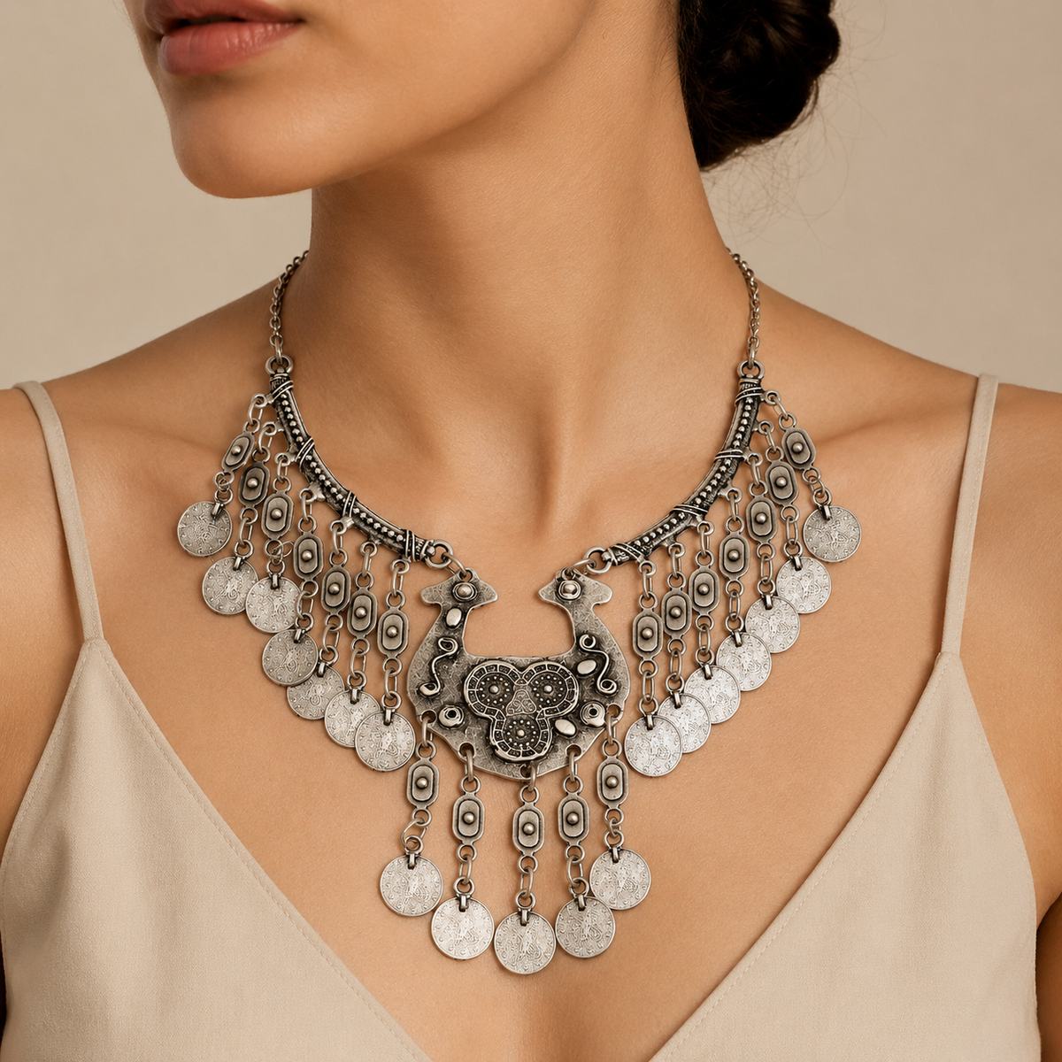 Silver-tone ornate necklace with a bold central pendant and dangling coin details.