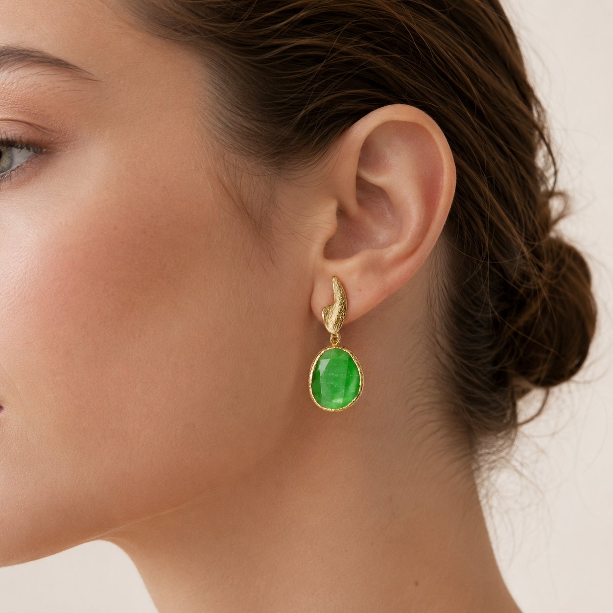 Pair of long drop earrings with bright green faceted stones and a textured gold-plated finish.
