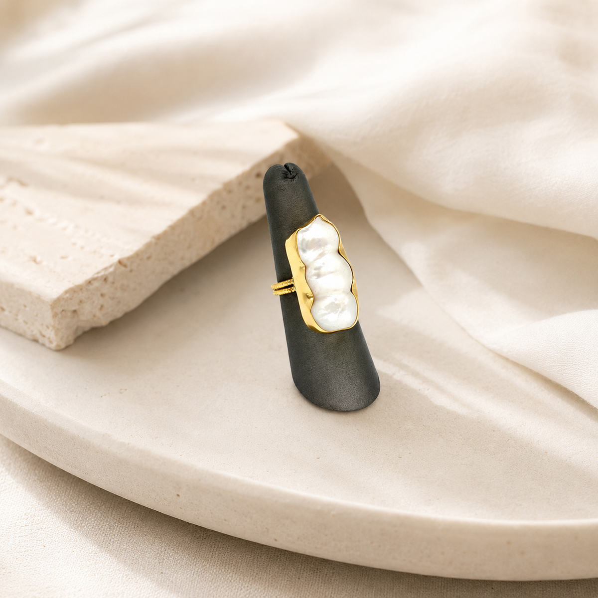 A gold-plated statement ring with a baroque pearl-inspired design.