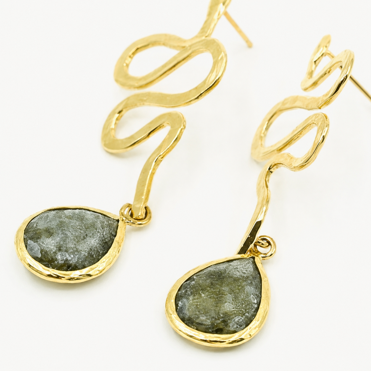 Close view of the snake-shaped gold-plated earrings and teardrop accents.