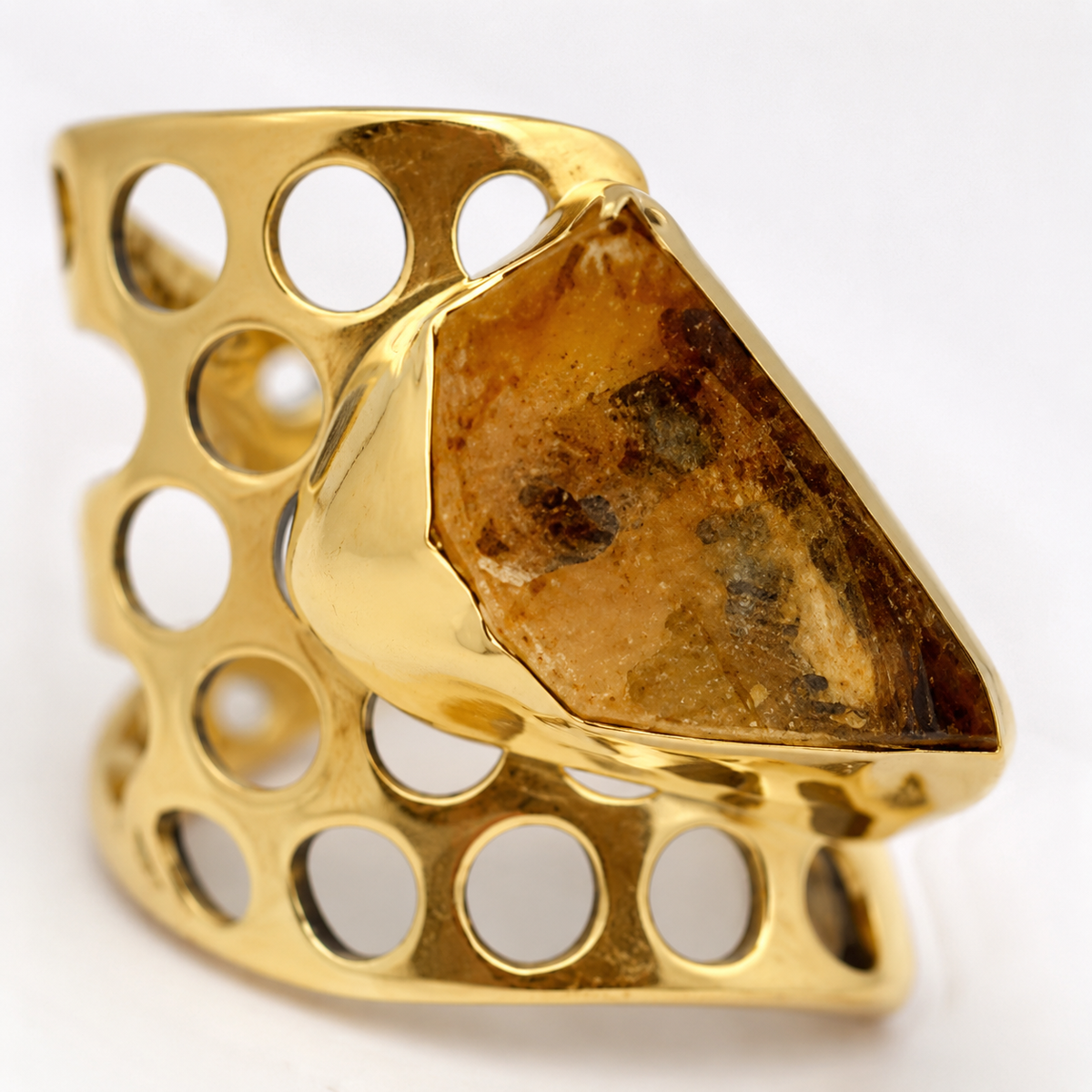 Close view of a rough citrine stone set in a gold-plated honeycomb ring.