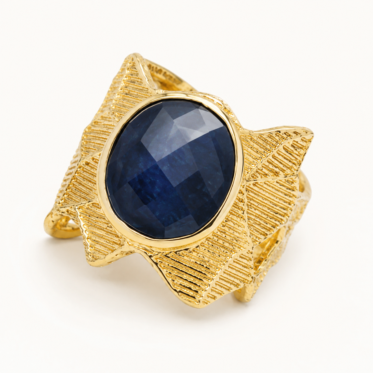 Close view of the textured gold-plated ring and faceted navy blue oval center stone.
