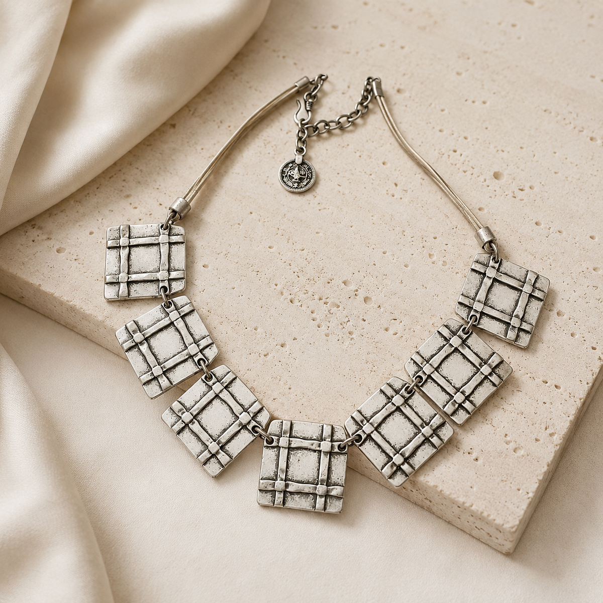Beige cord necklace with linked square pendants styled as a statement piece.