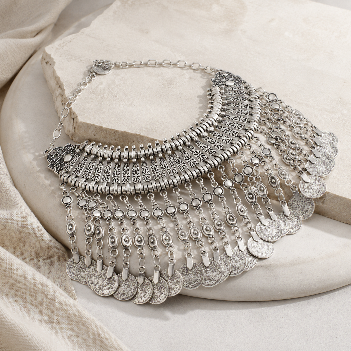 Angled view of a silver-tone coin fringe necklace with layered decorative details.