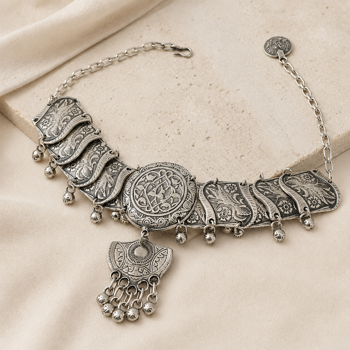 Angled view of a silver-tone filigree medallion choker necklace with decorative chain details.