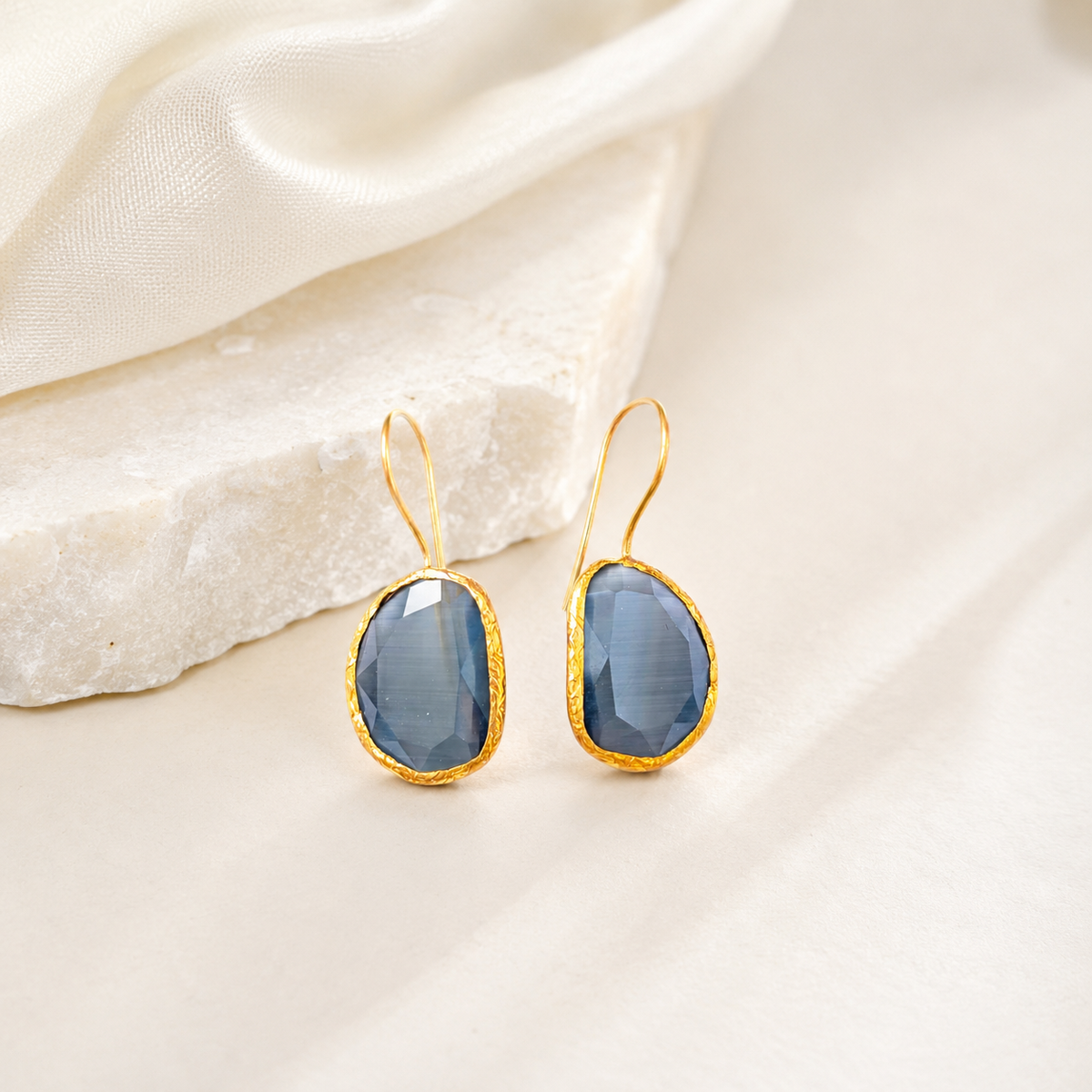 Gold-plated teardrop earrings with smoky gray stones on a white background.
