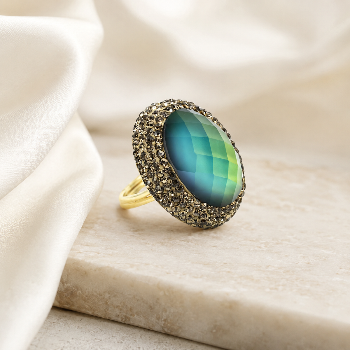 Round color-changing ring with a faceted blue-to-green center stone and gold-tone setting.