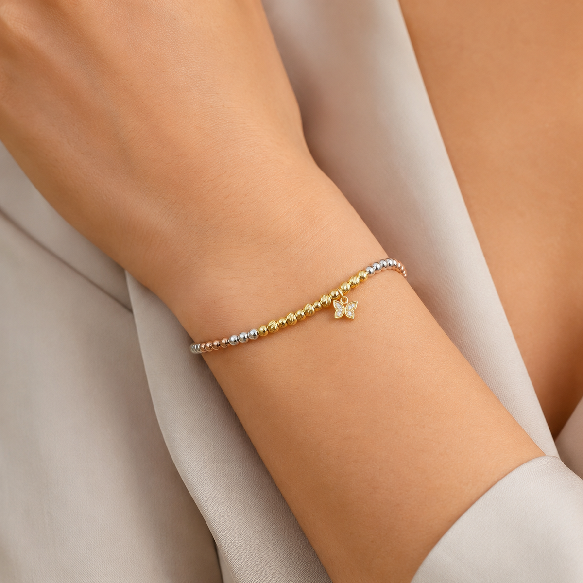 Bracelet with mixed metallic beads and a butterfly charm on a white background.