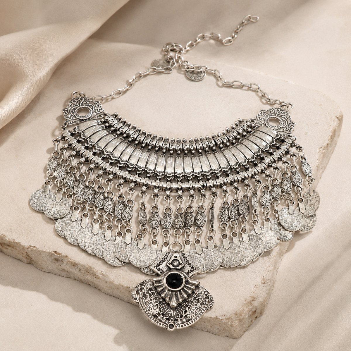 Silver-tone statement necklace with layered coin fringe and black stone pendant.