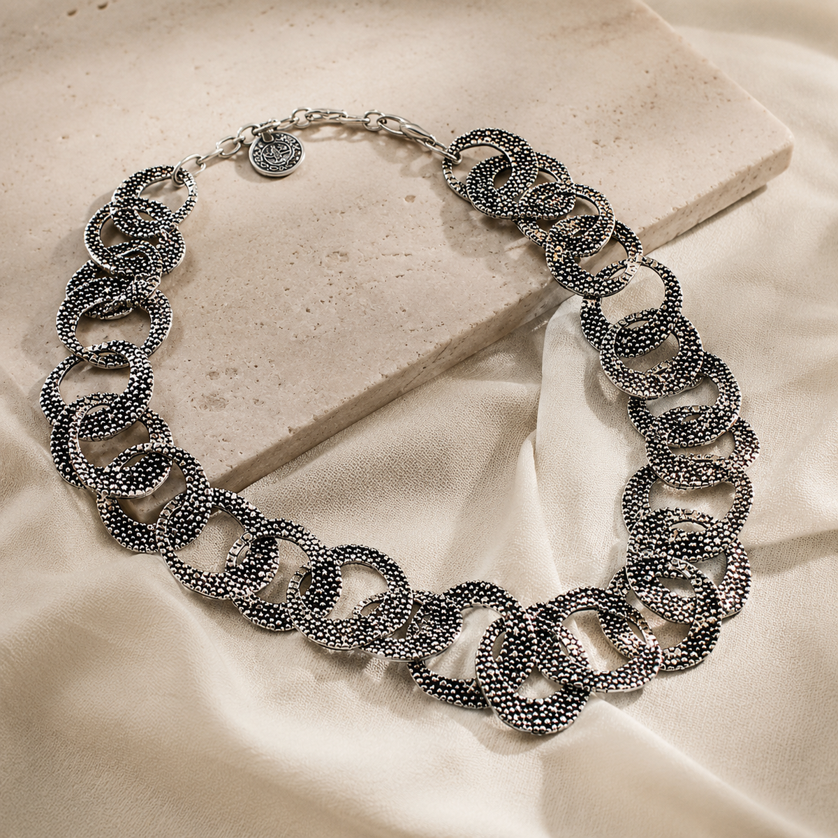 Angled view of a textured silver oval link necklace.