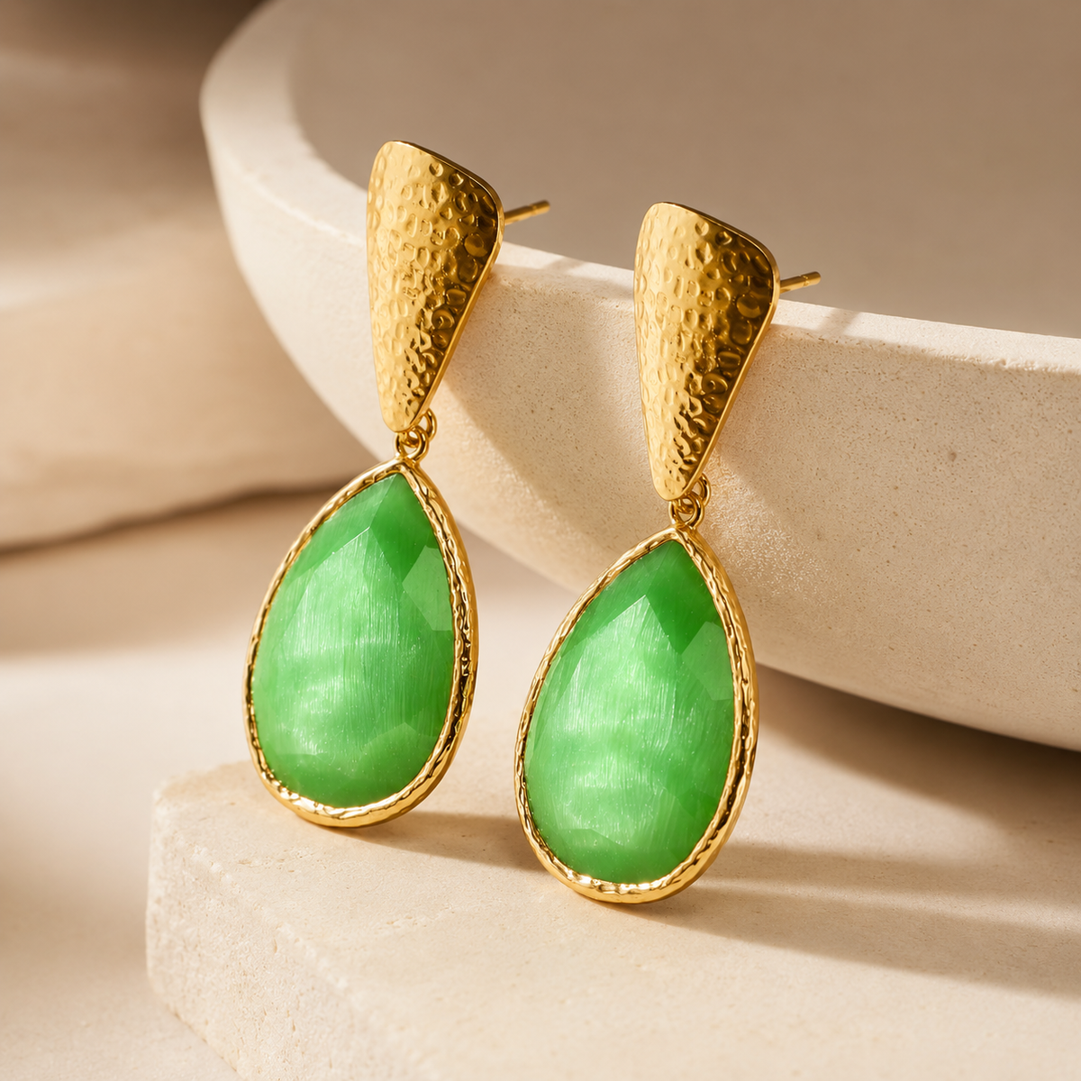 Angle view of green teardrop earrings with a textured gold finish.