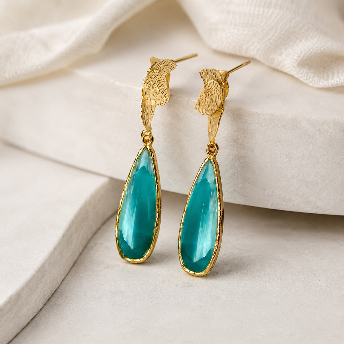Close-up of turquoise teardrop earrings with a gold-plated frame.